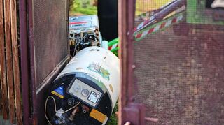 Eine alte Gastherme samt Warmwasserspeicher liegt ausgebaut auf dem Grundstück eines Einfamilienhauses.