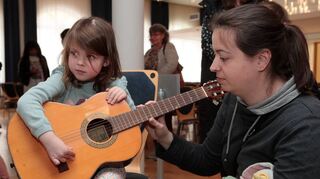 Bei Jahreskonzert der Jugendmusikschule Brühl gibt es anschließend Instrumente zum Anfassen und Ausprobieren – so zupfen Celia und Wiebke Meier ihre ersten Töne auf der Gitarre.