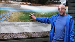 Armin Jendrysik (r.), Projektleiter des Artenschutzprojektes Sandrasen, erläutert den Gästen die neuen Nabu-Banner, die die einzigartige Tier- und Pflanzenwelt in den Sandgebieten beschreiben.