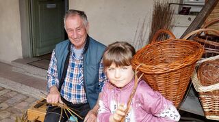 Marnja (6) schultert ein Füllhorn aus Weidenzweigen, das Korbmacher Edmund Gehrlein gefertigt hat.