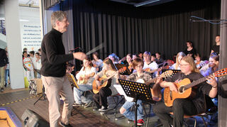 Otfried Kromer dirigiert die Gitarrenklasse 6b, die sich an Filmmusik und legendäre Stücke wie "We will rock you" wagen.