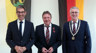 Staatssekretär Dr. Andre Baumann, Dieter Hoffstätter mit dem Bundesverdienstkreuz am Revers und Bürgermeister Uwe Grempels beim Festakt im Bürgersaal.