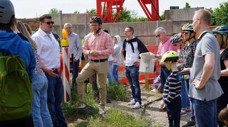 Bürgermeister Nils Drescher begrüßt die Neubürger auf der Baustelle und erläutert das Megaprojekt der Gemeinde.