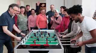 Am Tischkicker sind unterschiedliche Sprachen keine Barriere: Zum Neustart des Café Komm im Lutherhaus spielen und beobachten Reinhard (v. l.), Pfarrer Michael Dahlinger, Eva, Konrad, Silke, Oksana, Holger, Meral, Razim, Svitlana, Nadine und Jemil die erste Partie. Ab sofort ist das Café wieder zweimal pro Woche geöffnet.