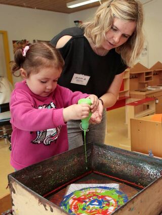 Natalie Wagner und die dreijährige Lucia spritzen ein kreatives Kunstwerk.