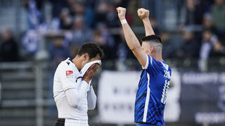 Im „Sechs-Punkte-Spiel“ zwischen dem SV Sandhausen und dem FC Hansa Rostock zieht Sandhausens Hamadi Al Ghaddioui nach Spielende das Trikot übers Gesicht, während Rostocks Ryan Malone den 2:1-Sieg bejubelt.