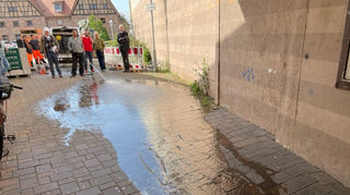 Wasser marsch: Kläger Adi Graf hat für den Ortstermin mit einem weiteren Gutachter ein Unternehmen beauftragt, das durch Bewässerung die Wege zeigt, die das Wasser vom Zehntscheunenplatz nach einem Regenereignis in Richtung Mauer (r.) nimmt.