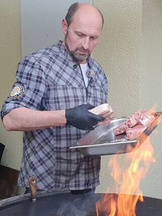 Meister Jürgen Gieße legt das Fleisch für den Hauptgang auf den Fassgrill.
