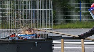Sascha Filsinger löst bei dem in einem Metallkäfig stehenden Batteriemodul einen Kurzschluss aus.