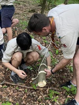 Stammesleiter Amon (r.) unterstützt die Jungs beim Binden der Holzstücke.