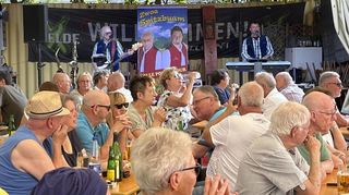 Die „Zwoa Spitzbuam“ spielen am Freitag zünftig zum Hähnchenfestauftakt auf. Die Biertischgarnituren sind gut gefüllt, die Menschen plaudern, lauschen und gönnen sich Kaltgetränke.