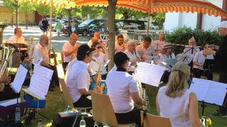 Ganz entspannt unter Schirmen und schattigen Bäumen spielt der Musikverein Neulußheim mit Unterstützung aus Altlußheim am Alten Bahnhof auf und begeistert das Publikum bei sommerlichem Wetter.