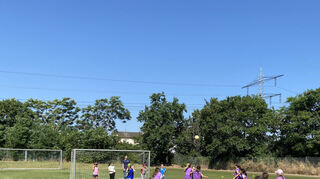 Team Lila lässt den Ball hoch fliegen und setzt sich gegen die andere Mannschaft durch.