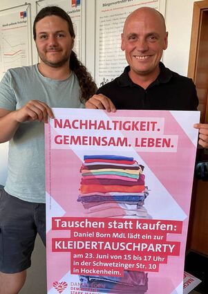 Jakob Breunig und Daniel Born mit dem Plakat zur Kleidertauschparty, die Nachhaltig-keit fördern soll.