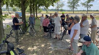 Auch bei einem Zwischenstopp am Neulußheimer Friedhof beantwortet Diplom-Geograph gerne Fragen der Teilnehmer, die der Einladung des Heimatvereins nachkommen, und die Umgebung auf dem Fahrrad erkunden.