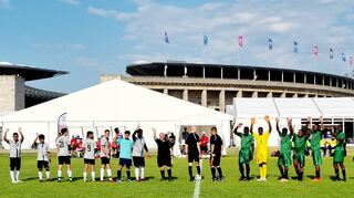 Die jamaikanischen Fußballer (r.), die am vergangenen Mittwoch noch auf dem Schwetzinger Schlossplatz gefeiert wurden, haben im ersten Spiel Deutschland 3:1 bezwungen. Im Hintergrund ist das Olympiastadion zu sehen.