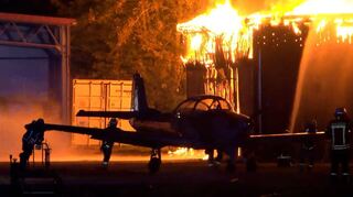 Während des Brandes bringen die Einsatzkräfte der Feuerwehr ein Flugzeug in Sicherheit. Etliche andere Modelle sind jedoch bereits zerstört worden.