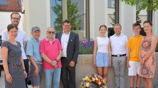 Pfarrerin Christiane Banse (v.l.) Sebastian Binder, katholische Kirche, Rudi Lerche, Ulrich Kobelke und Bürgermeister Nils Drescher zusammen mit Dr. Meinrad Gaa (Dritter von rechts) und desen Familie bei der Einweihung der Tafel.