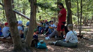 David Zahoor vom Kinder- und Jugendbüro Pumpwerk erklärt den kleinen Teilnehmerinnen und Teilnehmern die nächste Aktion bei den diesjährigen Waldwochen.