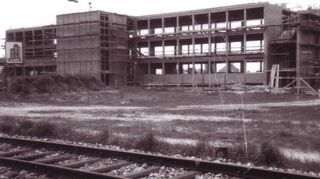 Das Brühler Görler-Werk im Rohbau, im Vordergrund erkennt man gut die damals noch bestehende Bahnlinie, die Brühl einerseits mit Ketsch, andererseits mit Mannheim-Rheinau verband. Heute ist das Haus das Hauptgebäude eines anderen weltweit agierenden Unternehmens: der Firma Hima.