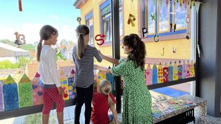 Bunte Stifte und Buchstabentiere zieren nun die Fenster im Obergeschoss. Lehrerin Julia Schuhardt hilft beim Befestigen.