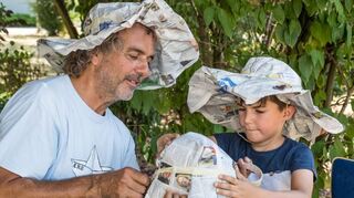 Peter Rösch von der Natur AG bastelt mit den Kindern Sonnenschutzhüte aus alten Zeitungen, Kreppband und Heftklammern.