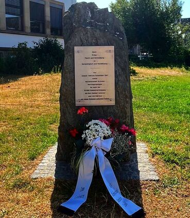 Der Gedenkstein ist zur Erinnerungszeremonie mit Blumen geschmückt.