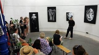 Die Gäste lauschen den Worten von Daniel Litta (im Hintergrund vor den Bildern). Mit seiner Kunst möchte er auf psychische Erkrankungen aufmerksam machen.
