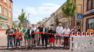 Symbolische Freigabe der Oberen Hauptstraße: Vertreter von Gemeinderat, Stadtverwaltung, Baufirma und Planungsbüro schneiden das rote Band in viele Teile und beenden so offiziell die Bauzeit.