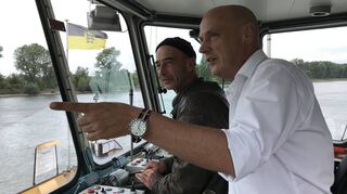 Der SPD-Landtagsabgeordnete und Landtagsvizepräsident Daniel Born (r.) lässt sich von Fährmann Manfred Beck erklären, wie die Geräte in der Führerkabine der Kollerfähre funktionieren.