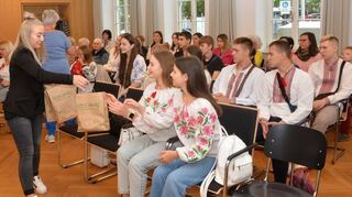 Auch aus Plankstadt gibt es Nützliches für den Aufenthalt – unter anderem eine schicke eine Trinkflasche mit Plankstadt-Aufdruck. Anneliese Strottner (verdeckt) und Vivien Schmitt verteilen hier gerade die Tüten an die traditionell gekleideten Ukrainer.