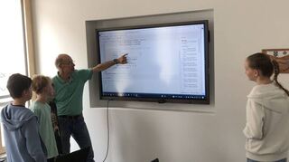 Michael Klein erklärt den Kindern den Quellcode, um eine Biene auf dem Bildschirm fliegen zu lassen.