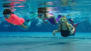 Diese drei Meerjungfrauen im Freibad fühlen sich beim schier schwerelosen Schweben unter Wasser sichtlich wohl.