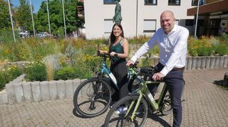 Rathaus-Azubi Alyssa Milano und Bürgermeister Timo Wangler präsentieren die beiden neuen E-Bikes, mit denen die Mitarbeiter der Gemeinde künftig dienstlich im Ort unterwegs sein können.