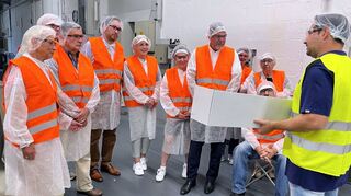 Produktionsleiter Patrick Rebmann präsentiert ein Sortiment von Kombidosen. Andreas Sturm (4.v.l.), Stadträtin Bärbel Hesping, CDU-Kreisgeschäftsführerin Birgit Fritz, OB Marcus Zeitler und die anderen CDU-Mitglieder sind beeindruckt.