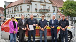 Gruppenbild am Kommandantenwagen mit dem Rathaus im Hintergrund: Ordnungsamtsleiterin Yvonn Rogowski (v. l.), Bürgermeister Matthias Steffan, der neu bestellte stellvertretende Kommandant Lars Hoffmann, der neue hauptberufliche Kommandant Lars Oehring, Oberbürgermeister Dr. René Pöltl und der scheidende Feuerwehr-kommandant Walter Leschinski.