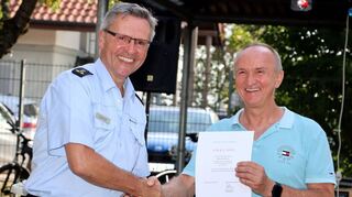 Der Leiter der Schutzpolizeidirektion des Polizeipräsidiums Mannheim, Joachim Scholl, (l.) überreicht dem langjährigen Leiter des Polizeireviers Hockenheim seine Ruhestandsurkunde, die dieser freudig annimmt.