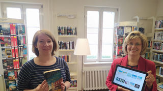 Die zwei Arten des Büchereiangebots: Anna-Kathrin Steinbauer (l.) präsentiert das Buch „Portugiesisches Erbe“ von Luis Sellano, Leiterin Annette Hörstel zeigt am Tablet das Online-System, in dem der Krimi ebenfalls zu finden ist.