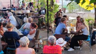 Der Biergarten im „Kleinen Plänkschder“ ist am Sonntagabend bestens besucht. Einige Gäste nutzen die spätsommerlichen Temperaturen für einen schönen Wochenendausklang, andere sind für das Konzert gekommen.