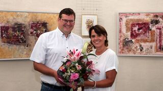 Bei der Eröffnung der Ausstellung unter dem Motto „Jahreszeiten“ mit Bildern von Nicole Fuchs im Wasserturm überreicht Bürgermeister Nils Drescher der Künstlerin Blumen.