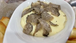 Zu den Pommes wird Trüffelsauce serviert.