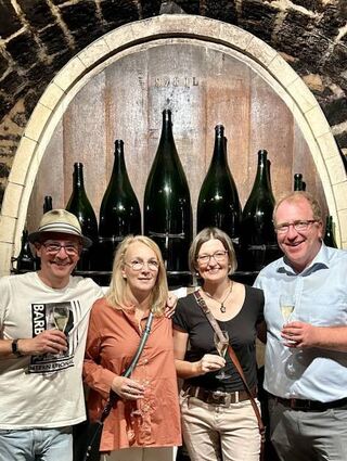 Bürgermeister Torsten Bechtel (r.) und Oberbürgermeister Dr. René Pöltl mit ihren Ehefrauen Hilke und Stefanie in den Räumen der Sektkellerei Schloss Wachenheim vor den beeindruckenden Sekt-Magnumflaschen (bis zu 26 Liter).