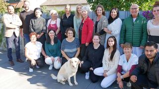 Neustart mit bekanntem Team: Vanessa Hauck (hinten, 5. v. l.) und Usman Ahmad (ganz links) mit einem Teil der Mitarbeiter und Pflegedienst-Hund „Luna“ im Garten des Pflegezentrums Sonnenschein.