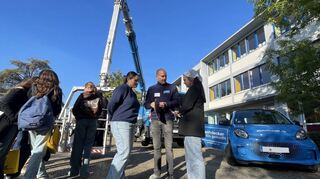 Paula Schneider (l.) und Maja Münkel (r.) bekommen bei Sebastian Winterbauer Einblicke über den Beruf des Dachdeckers. Im Hintergrund stehen Schüler Schlange, um eine Fahrt mit der Drehleiter zu wagen.