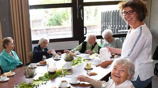 Gäste und Helfer plaudern angeregt. Theresia Müller (vorne.) kommt jedes Jahr gerne. Elisabeth Erhard vom Kirchenteam serviert die Getränke an den Tischen.