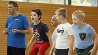 Ein Freudensprung, weil’s geklappt hat! Bei einem Spiel muss ein in der Mitte liegender Basketball mit den Handbällen getroffen werden, damit er zur gegnerischen Seite rollt.