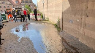 Zweites Gutachten im Mai 2023: Beim Ortstermin wird der Weg abfließenden Wassers vom Zehntscheunenplatz in Richtung Gebäudemauer (r.) nachvollzogen.