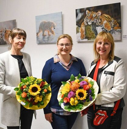 Birgit Zastrow (links) stellte bei der Vernissage als Malschülerin die Bilder ihrer Lehrerin genauer vor. Hier mit Bürgermeisterin Patricia Rebmann und Künstlerin Mila Müller vor den Tierportraits im Rathaus.