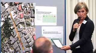Moderatorin Britta Opel erläutert die Abstimm-Möglichkeit der Teilnehmer an der Stellwand zur Ver-kehrsberuhigung in der Karlsruher Straße mit mehreren Varianten.