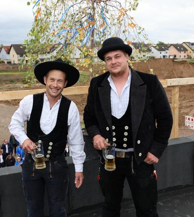 Mit einem dreifachen „Hoch“ begießen Janis Wiedemann (v. l.) und Luca Flock den Rohbau.